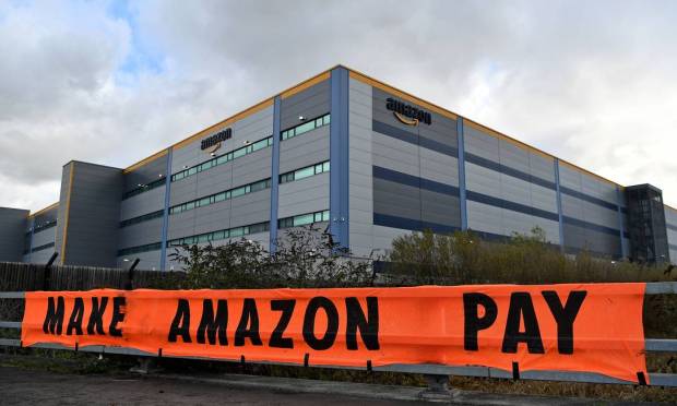 Ativistas exibem cartaz de protesto contra denúncias sobre manobras da gigante do varejo Amazon para não pagar devidos impostos onde atua, em Tilbury, a leste de Londres, na Inglaterra Foto: BEN STANSALL / AFP