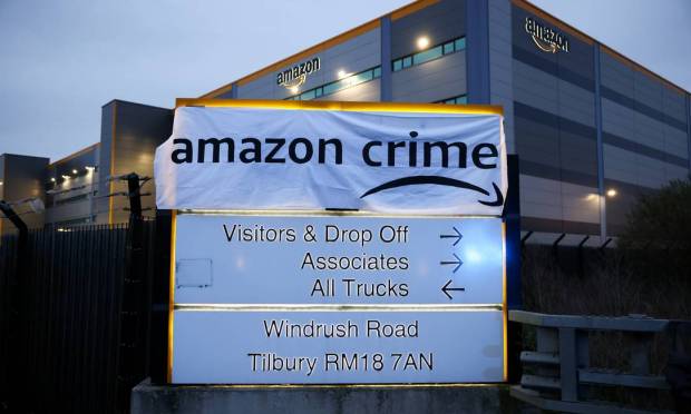 Ativistas sobrepõe cartaz de protesto à placa da entrada do centro de atendimento da Amazon em Tilbury, Essex, Grã-Bretanha Foto: HENRY NICHOLLS / REUTERS