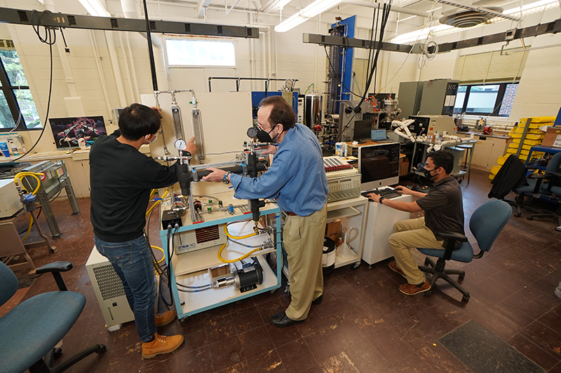 A new charging cable design developed by Purdue professor Issam Mudawar (center) and his students could reduce an electric vehicle’s charging time to under five minutes. (Purdue University photo/Jared Pike)